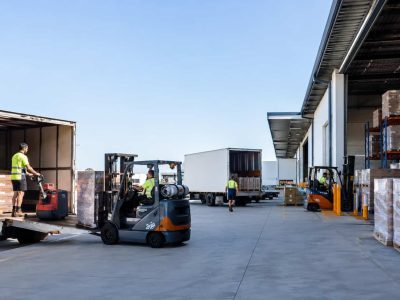 Warehouse staff moving pallets between freight trucks at a Perth logistics loading dock