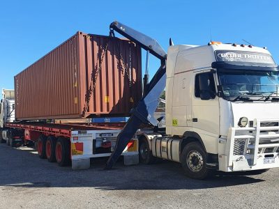Side loader trailer truck being used to transport shipping container
