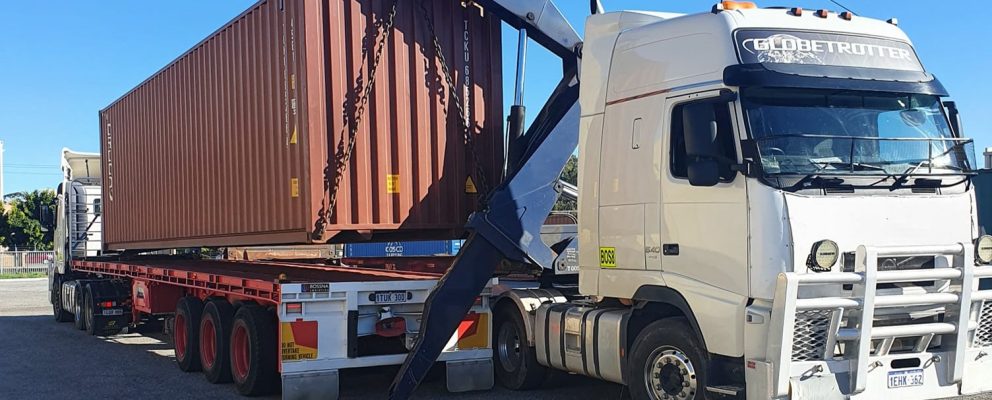 Side loader trailer truck being used to transport shipping container